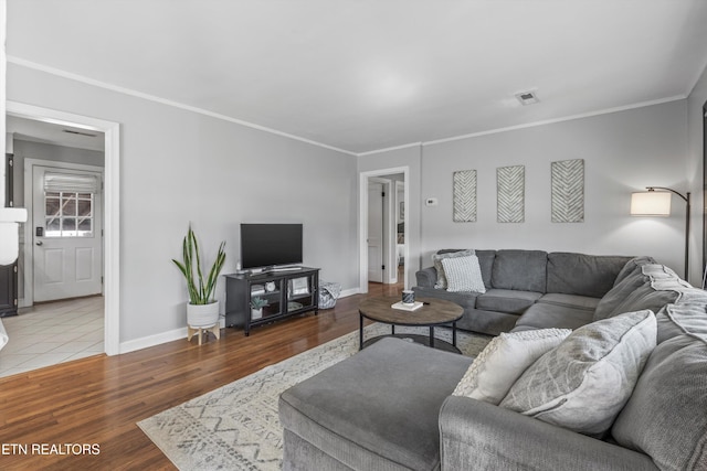 living area with baseboards, crown molding, visible vents, and wood finished floors