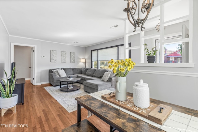 living room featuring ornamental molding, visible vents, baseboards, and wood finished floors