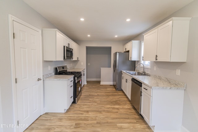 kitchen with light wood-type flooring, appliances with stainless steel finishes, white cabinetry, and sink