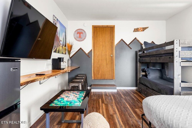 bedroom featuring stainless steel refrigerator, dark hardwood / wood-style flooring, and radiator