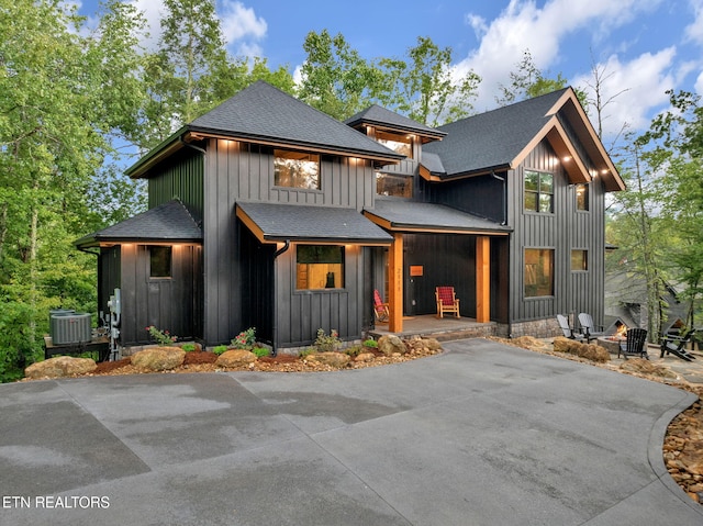 modern farmhouse with central AC, an outdoor fire pit, board and batten siding, and a shingled roof