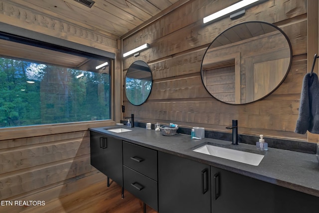 full bath with wood walls, wood ceiling, and a sink