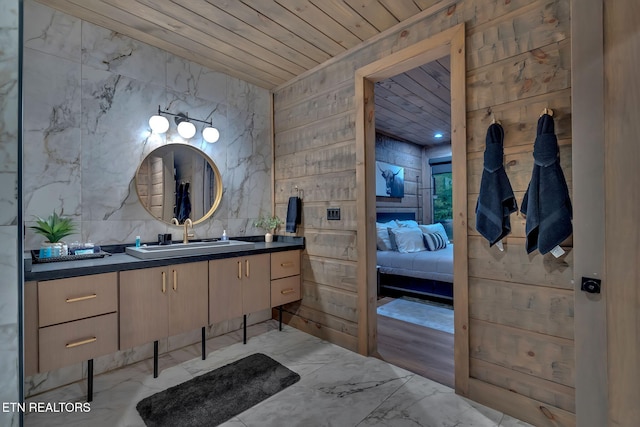 ensuite bathroom with wood ceiling, marble finish floor, connected bathroom, and vanity