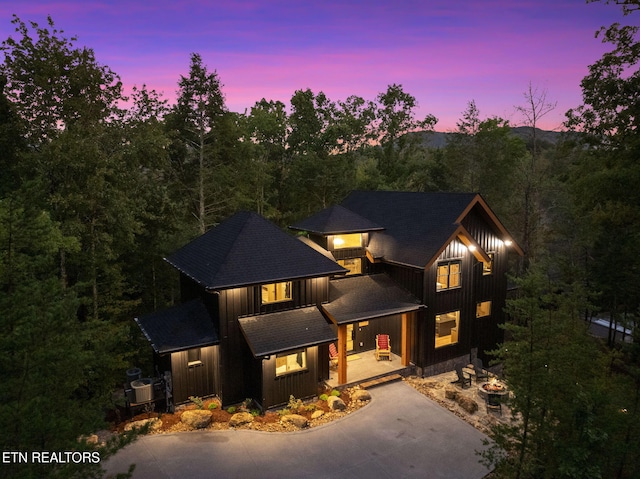 view of front of property featuring driveway, an outdoor fire pit, a porch, and board and batten siding