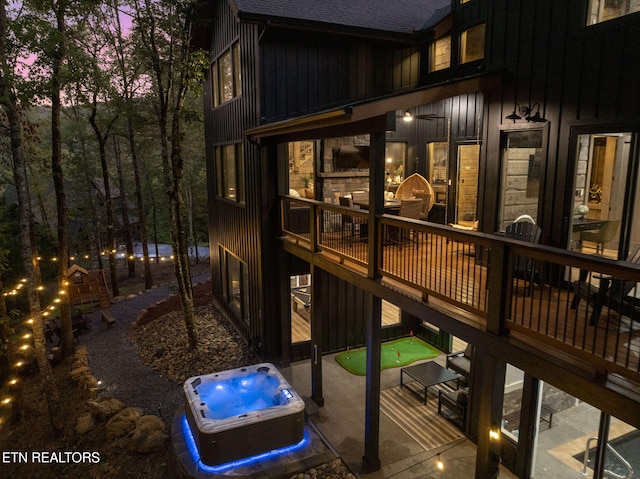 exterior space featuring an outdoor hot tub, board and batten siding, and roof with shingles