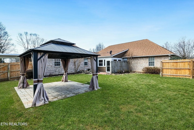 back of house featuring a lawn, a patio, fence, a gazebo, and brick siding