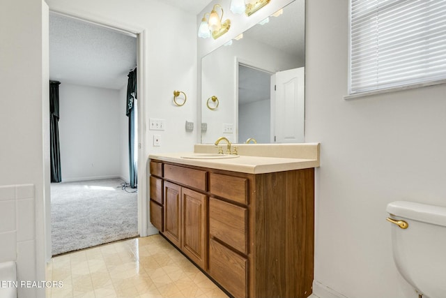 bathroom with baseboards, vanity, toilet, and a textured ceiling