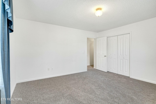 unfurnished bedroom featuring a textured ceiling, carpet floors, a closet, and baseboards