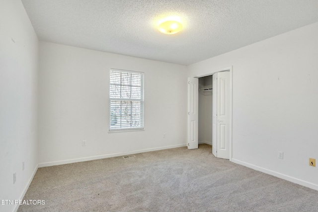 unfurnished bedroom with a closet, baseboards, a textured ceiling, and light colored carpet