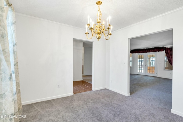 unfurnished room with baseboards, dark colored carpet, a textured ceiling, crown molding, and a notable chandelier