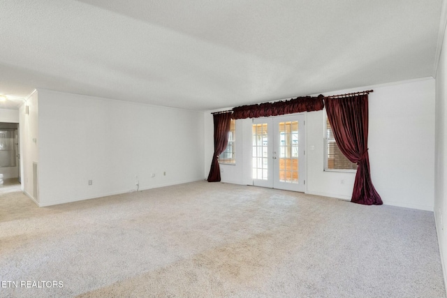 spare room with french doors, light colored carpet, and a textured ceiling