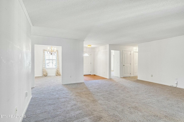 spare room featuring a textured ceiling, crown molding, baseboards, and light colored carpet