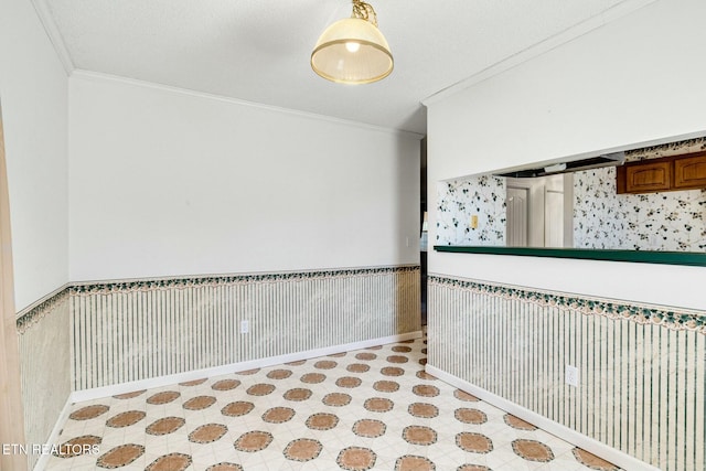 spare room featuring crown molding and wainscoting