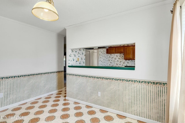 unfurnished room featuring wainscoting, crown molding, and light floors