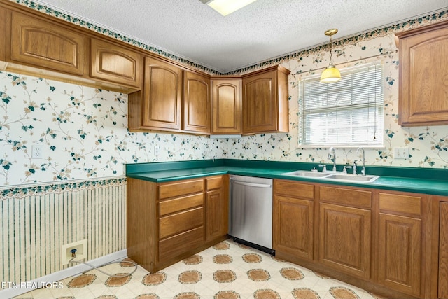 kitchen with a sink, wallpapered walls, dark countertops, and stainless steel dishwasher