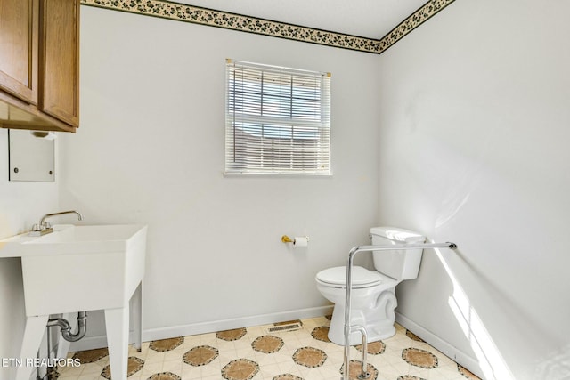 half bath with baseboards and toilet