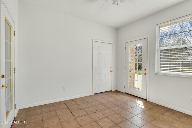 entryway with a textured ceiling, light tile patterned floors, a ceiling fan, and baseboards