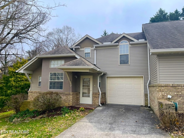 view of front of home with concrete driveway, an attached garage, brick siding, and roof with shingles