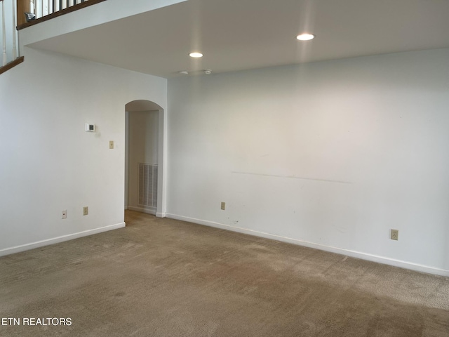 unfurnished room with arched walkways, visible vents, baseboards, and carpet floors