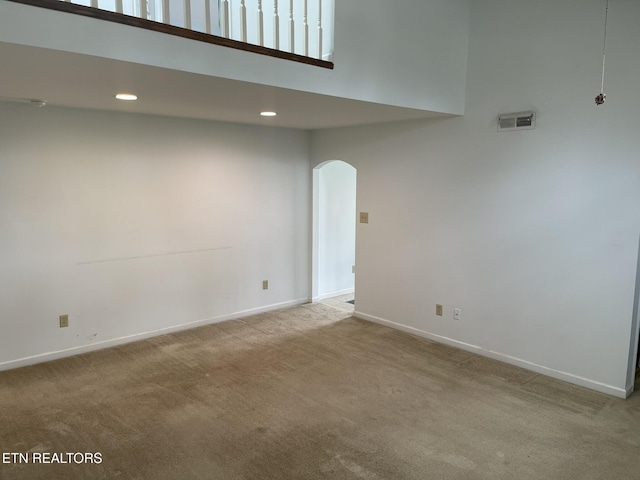 empty room featuring carpet, visible vents, baseboards, recessed lighting, and arched walkways