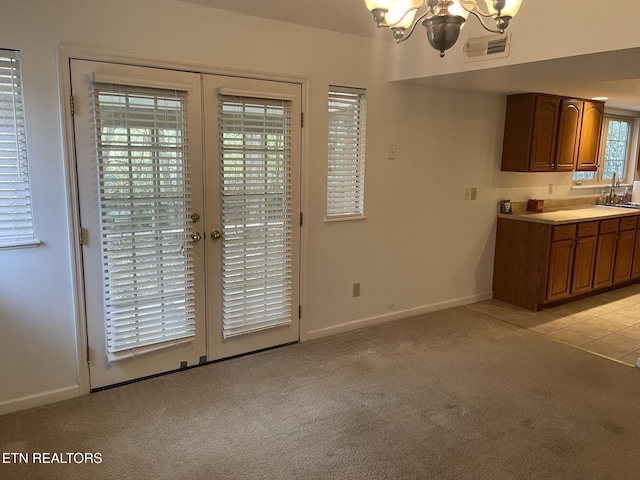 unfurnished dining area featuring visible vents, a sink, french doors, light colored carpet, and a chandelier