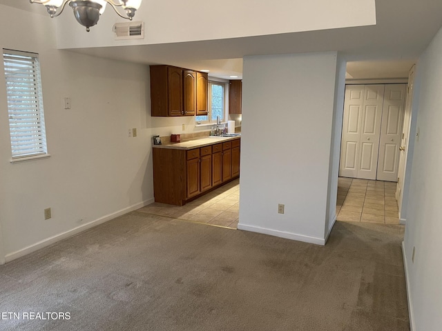 kitchen with a sink, visible vents, and light carpet