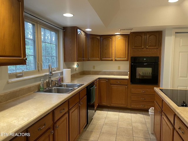 kitchen with light tile patterned floors, a sink, black appliances, light countertops, and brown cabinets