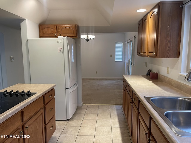 kitchen with a sink, freestanding refrigerator, light tile patterned flooring, light countertops, and black electric stovetop