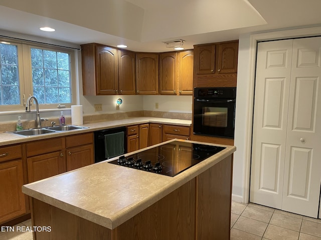 kitchen with light tile patterned floors, a sink, black appliances, light countertops, and a center island