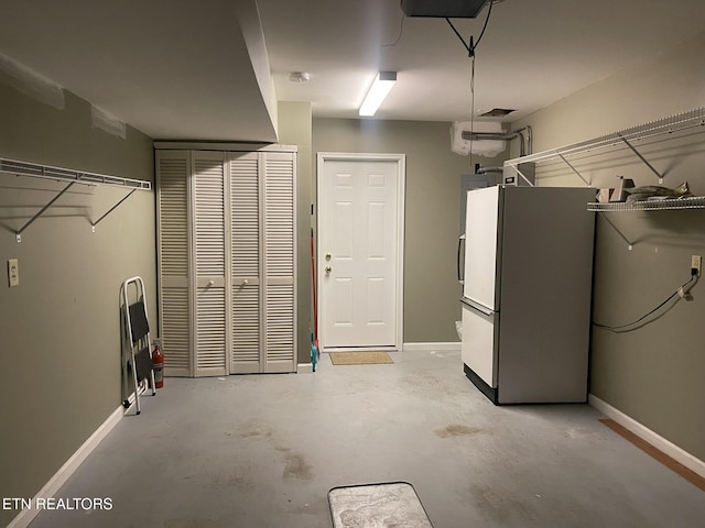 garage featuring baseboards and freestanding refrigerator