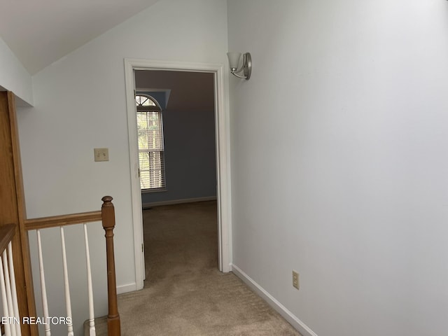 corridor with baseboards, light carpet, and lofted ceiling