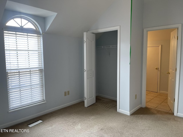 unfurnished bedroom featuring vaulted ceiling, multiple windows, a closet, and carpet floors