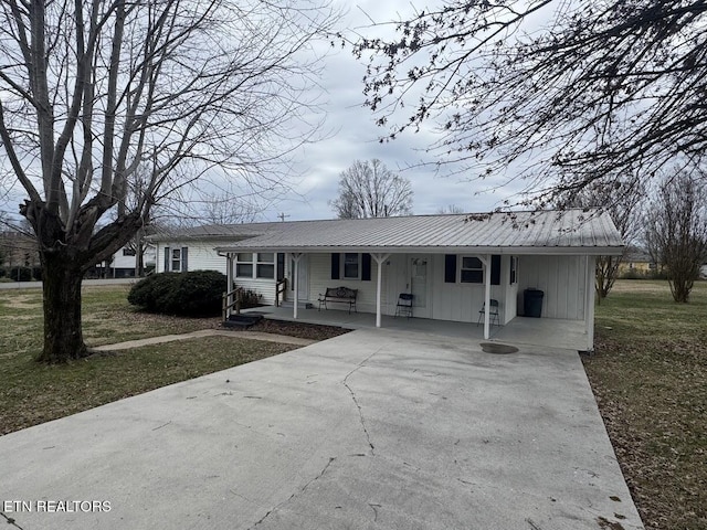 single story home featuring driveway, metal roof, a carport, a front lawn, and board and batten siding