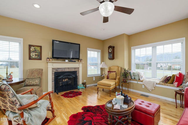 living room featuring light wood-type flooring, a wealth of natural light, ceiling fan, and a fireplace