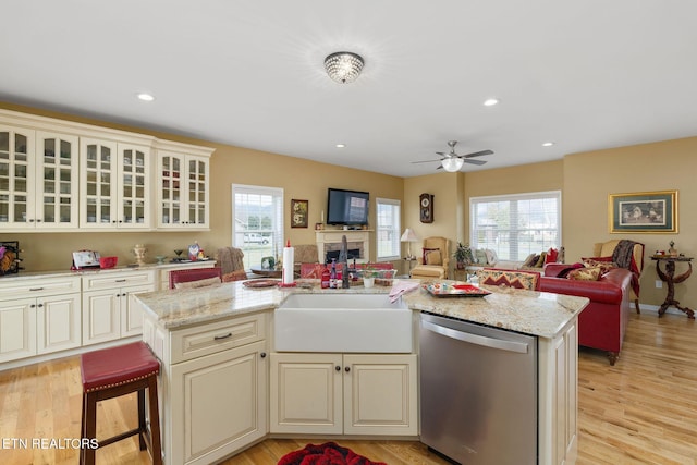 kitchen with stainless steel dishwasher, a breakfast bar, cream cabinets, and a center island