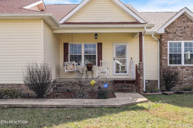 property entrance with covered porch and a lawn