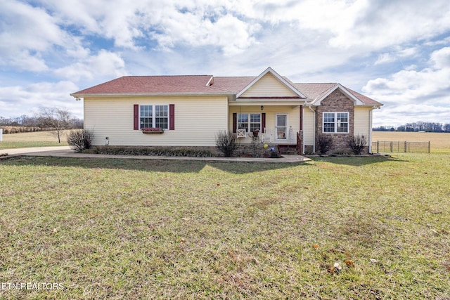 ranch-style home featuring covered porch and a front lawn