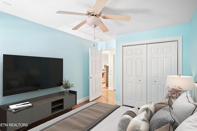 bedroom with a ceiling fan, a closet, light wood-style flooring, and baseboards