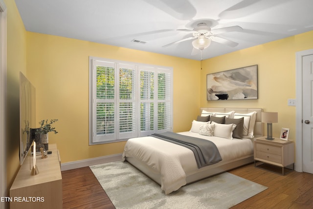 bedroom featuring a ceiling fan, visible vents, baseboards, and dark wood-style flooring