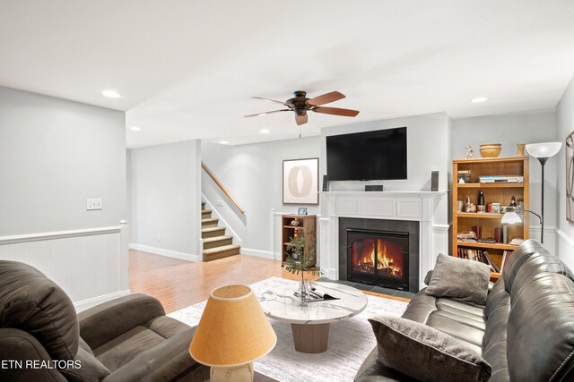 living room featuring light wood-type flooring, a fireplace with flush hearth, stairway, and recessed lighting