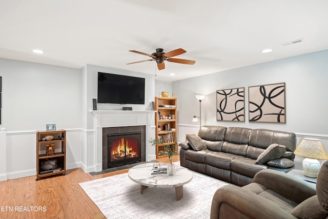 living area featuring recessed lighting, visible vents, a fireplace with flush hearth, wainscoting, and light wood-type flooring