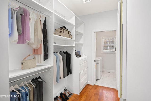 spacious closet featuring washer / dryer and marble finish floor