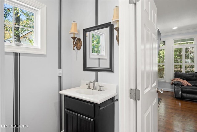 bathroom with recessed lighting, ornamental molding, vanity, wood finished floors, and baseboards