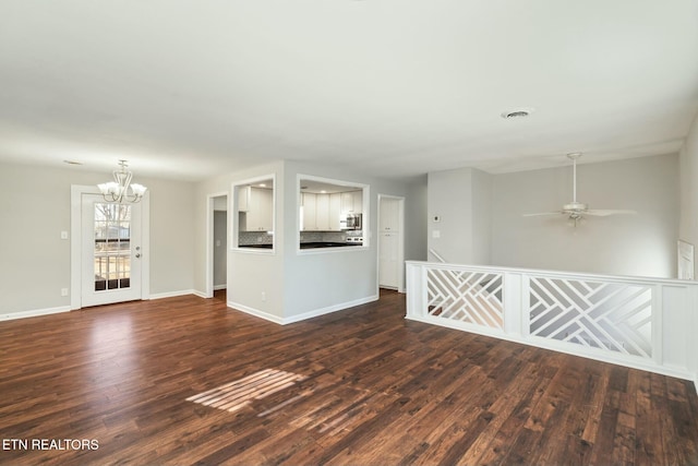 empty room with dark wood-type flooring and ceiling fan with notable chandelier