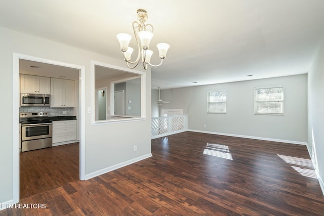 interior space featuring ceiling fan with notable chandelier and dark hardwood / wood-style floors