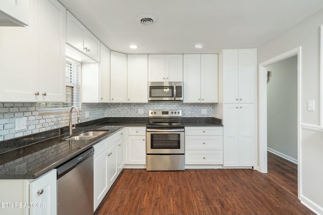 kitchen with sink, stainless steel appliances, dark wood-type flooring, white cabinets, and decorative backsplash