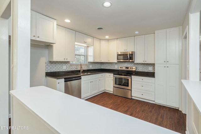 kitchen featuring stainless steel appliances, dark hardwood / wood-style flooring, sink, tasteful backsplash, and white cabinets