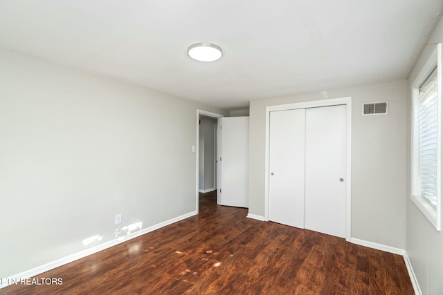 unfurnished bedroom featuring multiple windows, a closet, and dark hardwood / wood-style floors