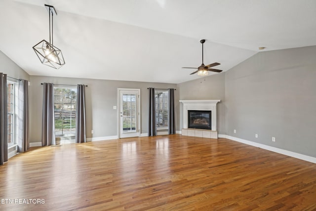 unfurnished living room featuring baseboards, lofted ceiling, ceiling fan, light wood-type flooring, and a fireplace