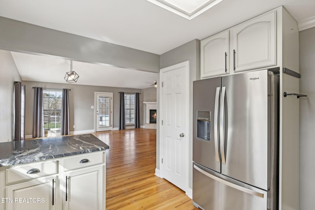 kitchen with open floor plan, dark stone countertops, stainless steel fridge, and white cabinets